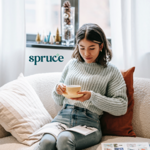 A woman reading a book, holding a cup of coffee in her clean apartment. Spruce logo to the left of her.