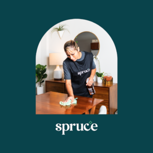 Image of Spruce cleaning pro wiping a wooden dining room table, inside of an arched box with the Spruce logo underneath.