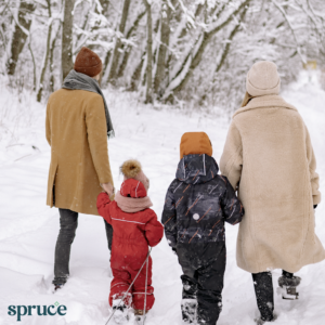 A family of 2 adults and 2 children walking in the snow. Spruce logo in the bottom left corner.