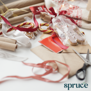 A messy table covered with wrapping paper scraps and supplies. Spruce logo in bottom right corner.